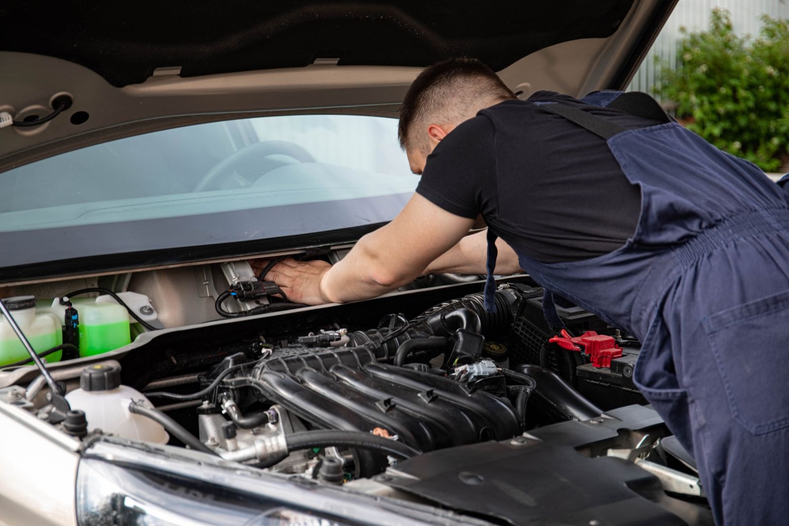Meccanico al lavoro sul vano motore di un'auto durante la manutenzione